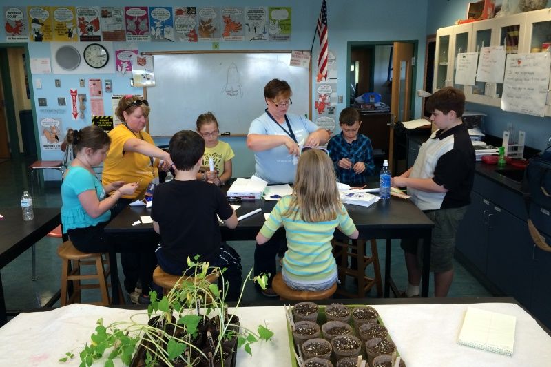 Student teacher with UMPI shirt in the classroom working on an experiment with kids