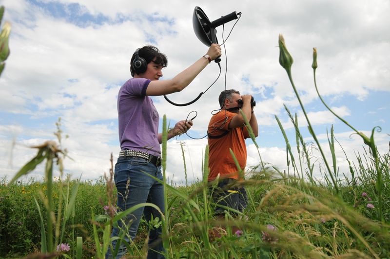 Student with Professor working with equipment in a field with tall grass