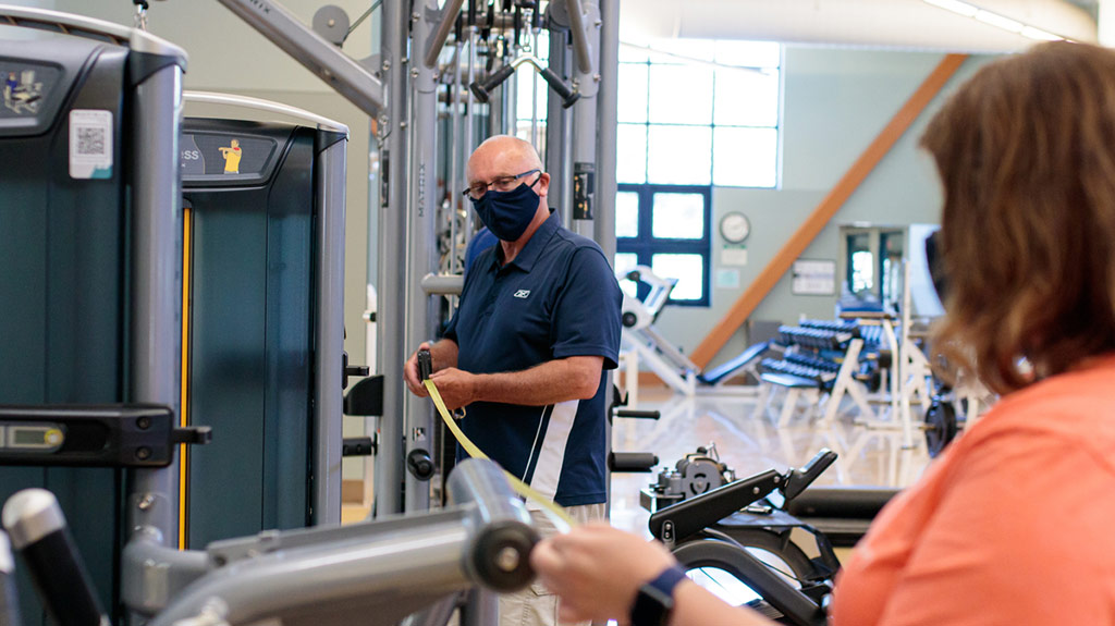 Photo of Dick Gardiner measuring space between exercise machines with a tape measure