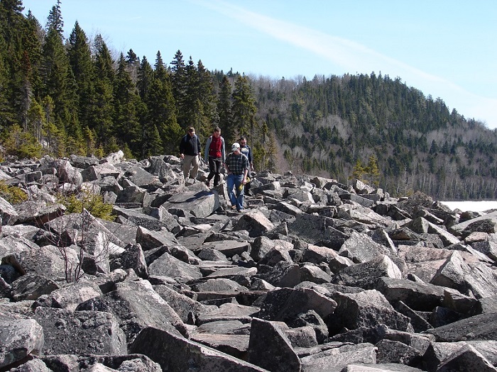 Photo of students and professors walking on large rocks next to the water