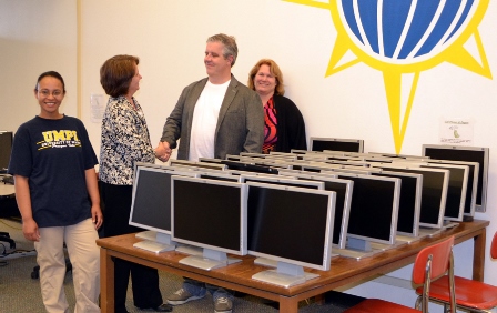 Photo of four UMPI officials with many donated computer monitors