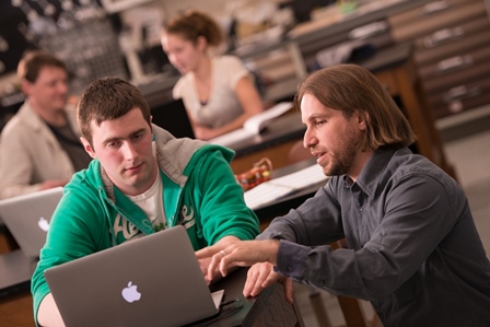 Photo of four people using laptops in class