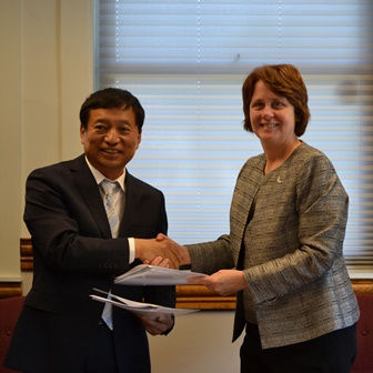 Photo of President Schott shaking hands with an official from Siyuan University after signing an agreement