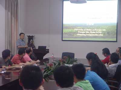 Photo of Dr. Wang teaching a class, using a projector as an aid