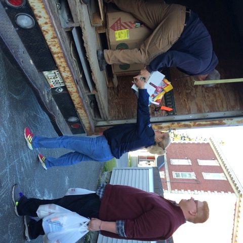 Photo of three people unloading food from the back of a truck