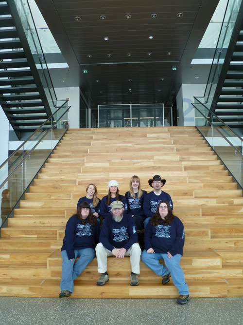 Seven Ecology Club members sitting on the wooden steps with matching sweatshirts