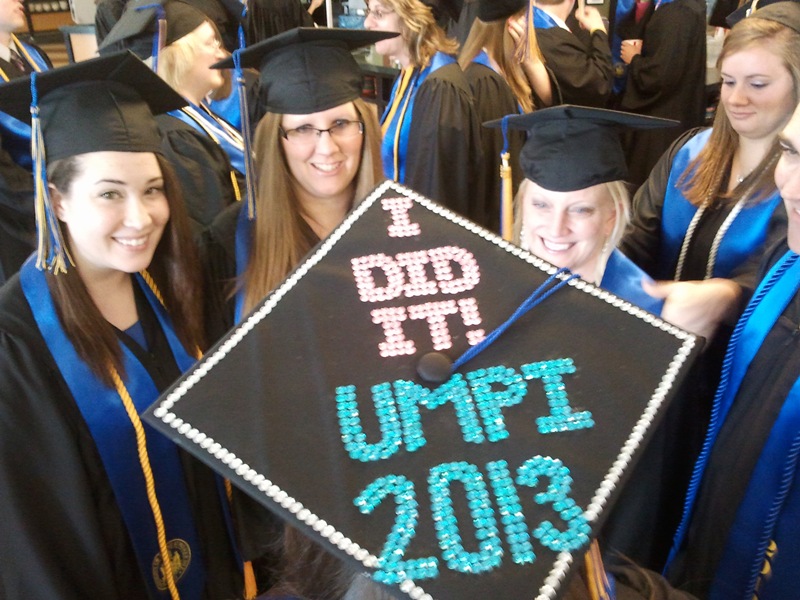 Photo of three UMPI 2013 graduates with a cap decorated with text "I DID IT! UMPI 2013"