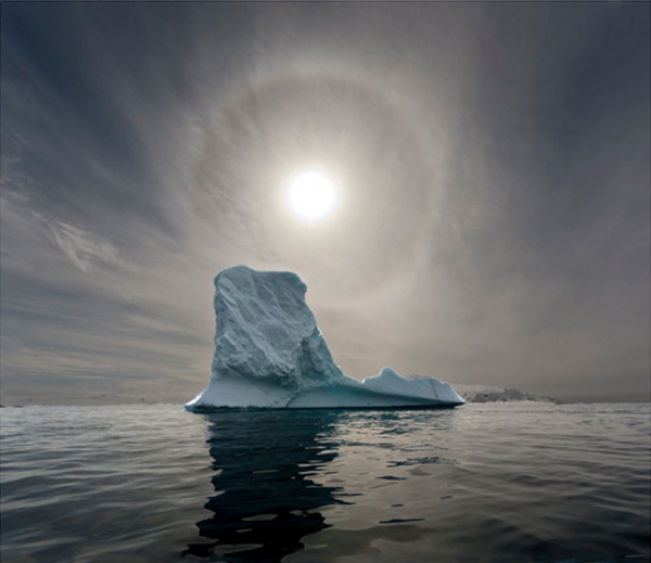 Photo of an iceberg with the sun in the backdrop