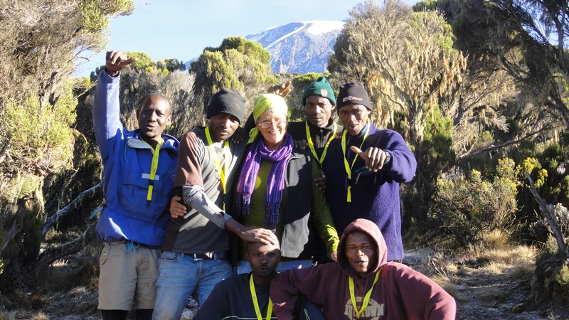 Photo of UMPI Professor Shirley Rush with six others posing in front of Mt. Kilimanjaro