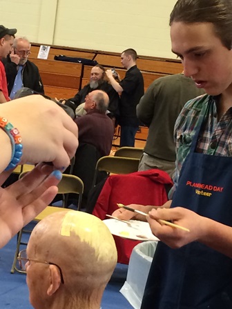 Photo of person getting their head painted yellow for Planet Head Day