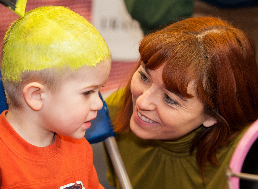 Photo of child getting his head painted yellow with adult smiling for Planet Head Day