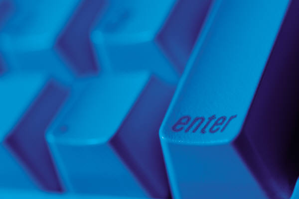 Photo of computer keyboard, focused on the "enter" key, whole picture is blue-tinted