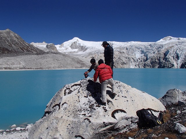 Three people on a rock by a lake in Bhutan