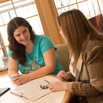 Two students discussing a book