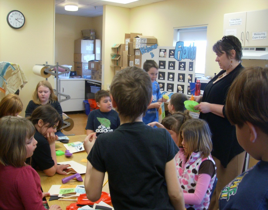 Eleven children gathered around a classroom table with a teacher