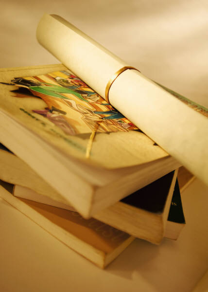 Four books stacked on each other, with a rolled-up diploma on top - in yellow tint