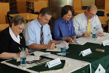 Photo of four officials signing transferability agreement