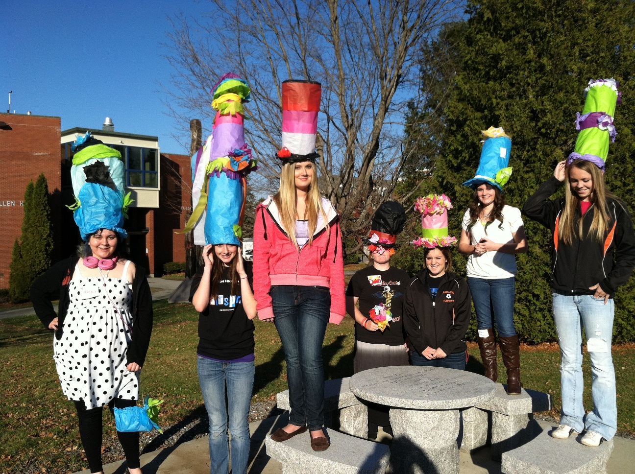 Seven middle school students posing with colorful funny hats