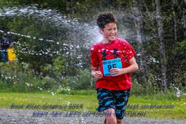 Photo of child running through sprayed water at triathlon