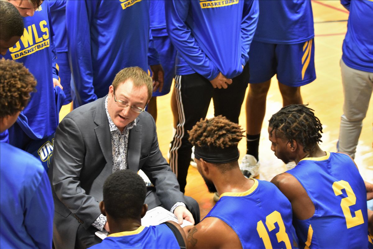 Photo of Coach Dan Kane in a basketball huddle during a timeout