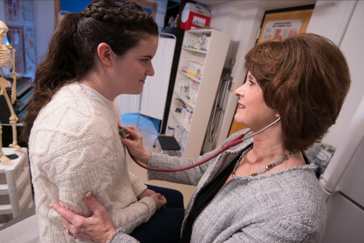 Photo of Linda Mastro examining a student with a stethoscope