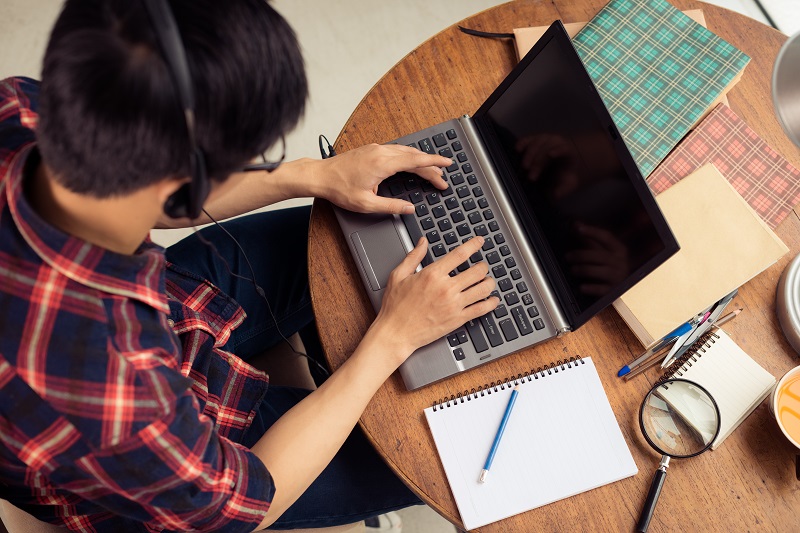 Photo of student using a laptop computer with headphones