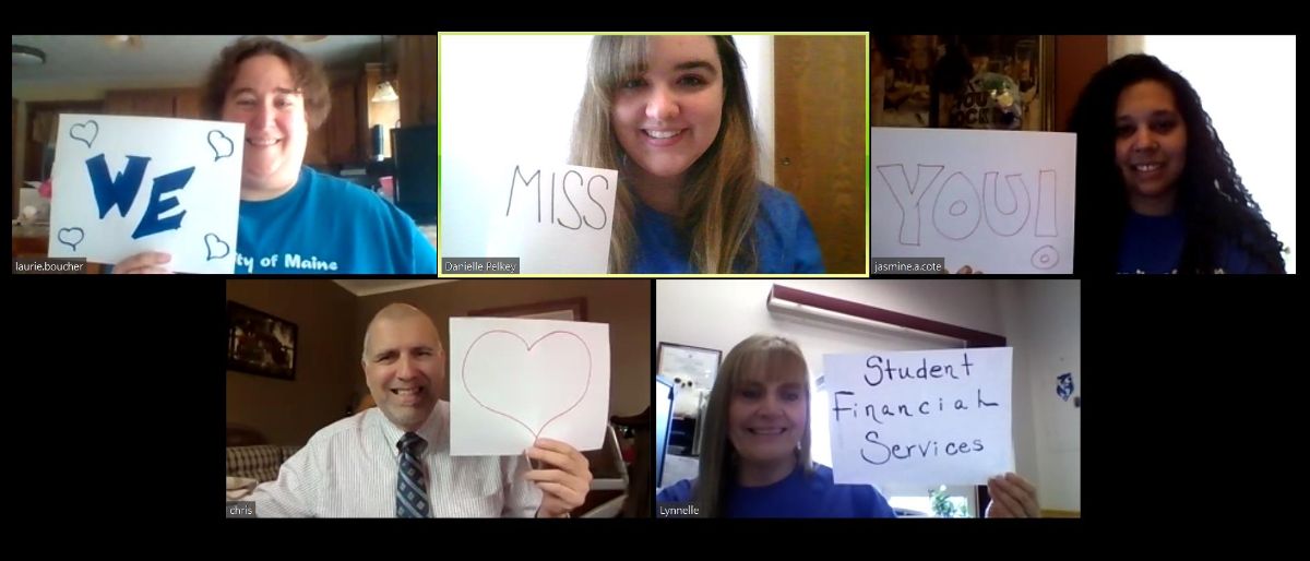 Student Financial Services staff on a Zoom call holding up signs saying "We miss you!"