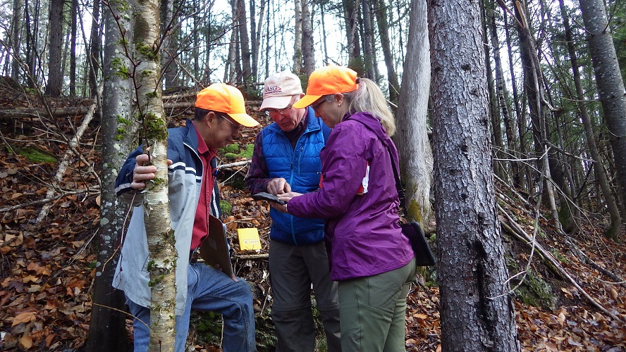 Photo of Dr. Chunzeng Wang working with former State Geologist Dr. Robert Marvinney and Amber Whittaker, Maine Geological Survey Senior Geologist and current coordinator for northern Maine projects, at Pennington Mountain.